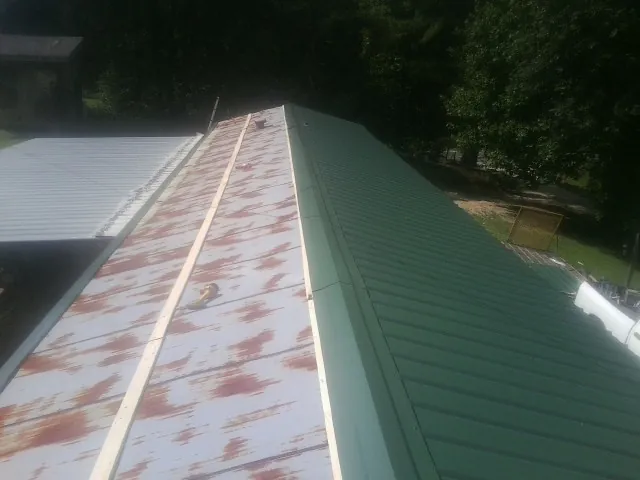 Old rusted panels beside newly installed green metal roofing — Wind Damage Roof Repair by Roofing Brothers in Lake Ozark