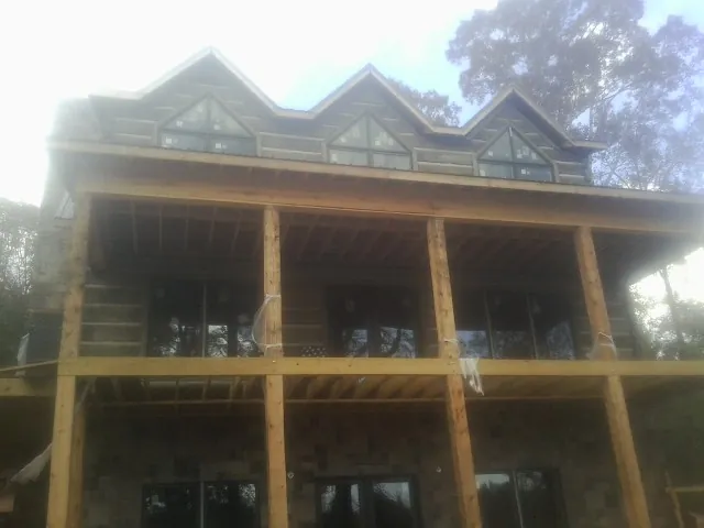 Dormers and porch framing on a large log home under construction — Roof Coating work by our crew in Lake Ozark