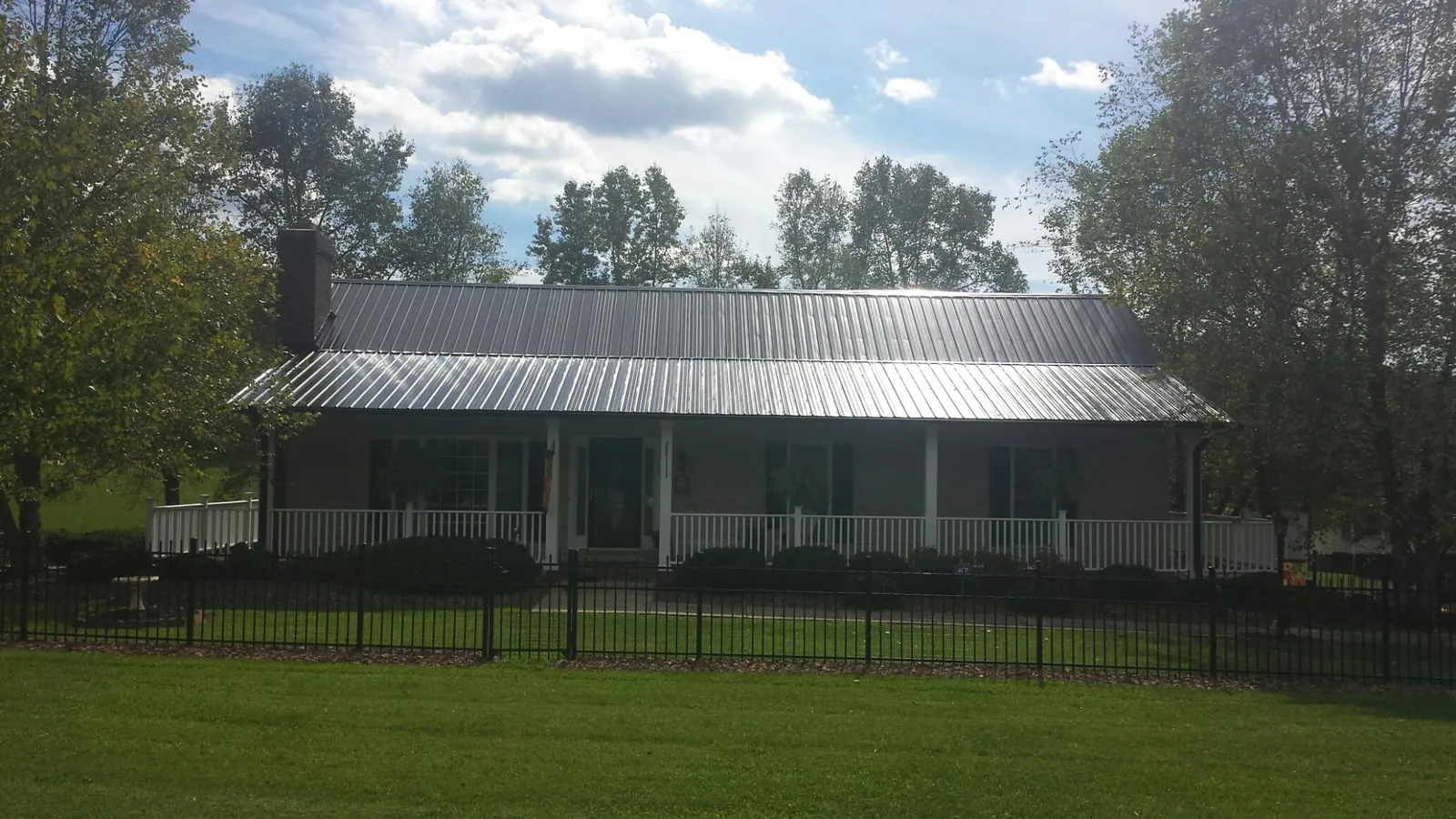 Gray metal roof on a brick ranch with a full width front porch — Gutter Guard Installation work by our crew in Lake Ozark
