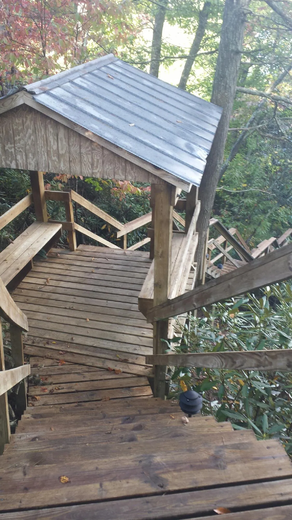 Metal roofed shelter over wooden steps on a wooded walkway — Skylight Repair & Installation work by our crew in Lake Ozark