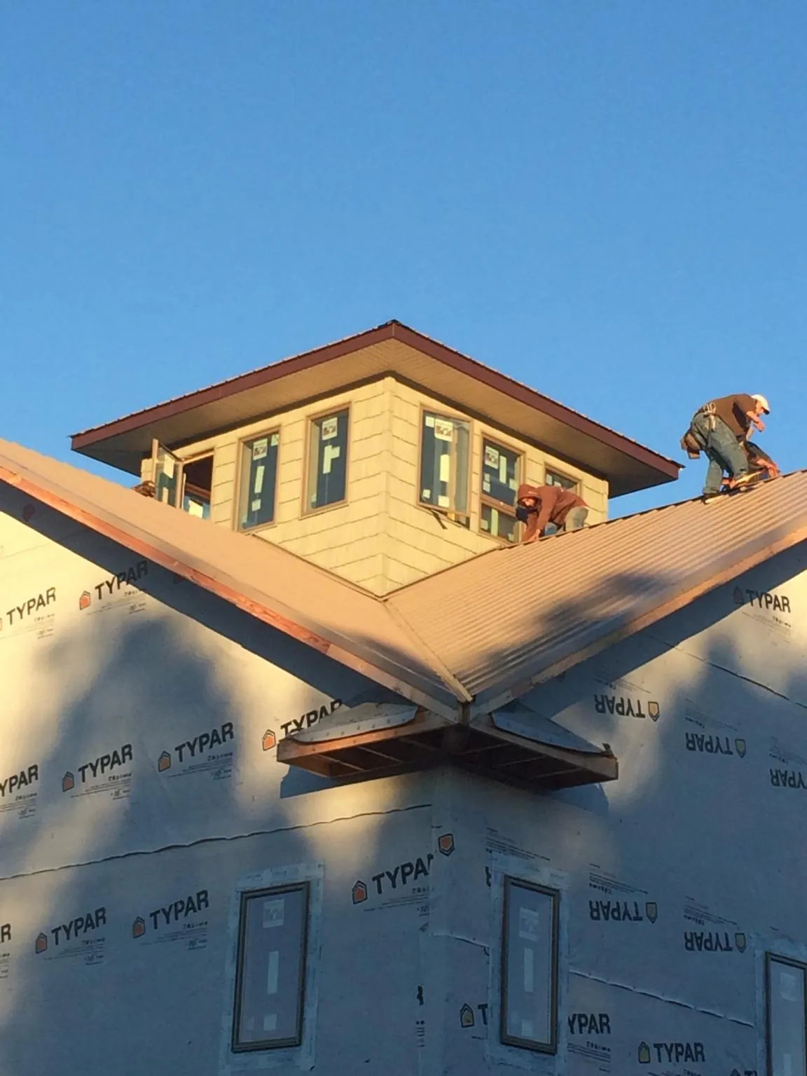 Roofers working around a rooftop cupola on a new metal roof at sunset — Roof Waterproofing in Lake Ozark by Roofing Brothers